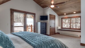 A bedroom with a large bed, a ceiling fan, a TV, a window seat, and a view of snow-covered trees. -   Luxury Home, Ideal Winter Ski-in/Ski-out or Summer Basecamp (Big Sky)