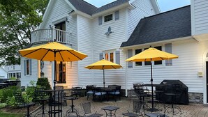 Une terrasse avec des sièges d’extérieur, des parasols jaunes et un barbecue.
