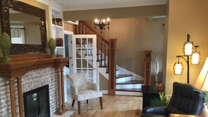 Un salon avec une cheminée, un escalier, un canapé en cuir et une table basse.