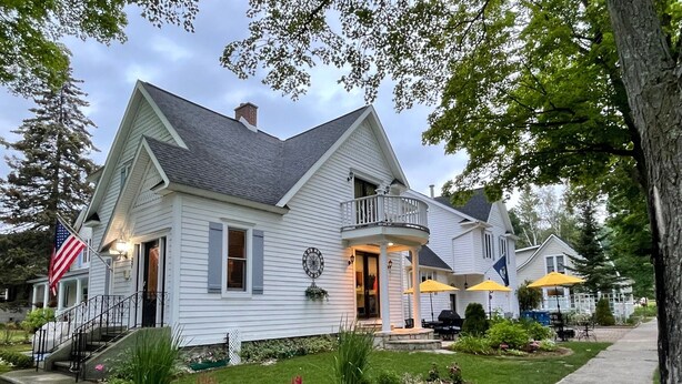Une maison à deux étages avec un porche, un petit jardin et un drapeau.