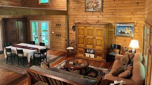 A cozy cabin interior with a dining area, sofa, and a wooden cabinet.