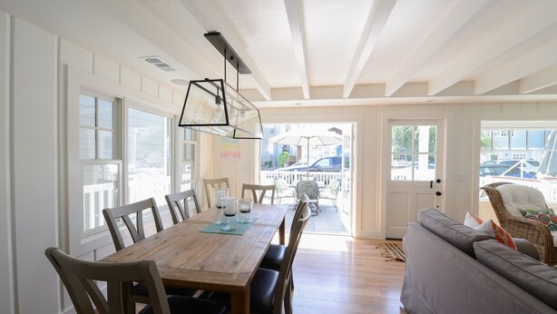 Un comedor con mesa y sillas de madera, un sofá y vistas al exterior.