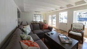 Una sala de estar moderna con un sofá modular, una mesa de centro y un sillón de mimbre.