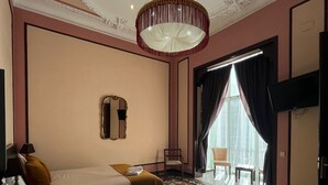 Ett hotellrum med två sängar, en kristallkrona, en stor spegel och utsikt över omgivningarna.