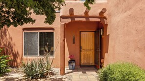 A stucco building with a wooden door, a window with blinds, and a welcome sign. - Beautiful Santa Fe Oasis. Golf, hiking & biking paradise, 20 min drive to UofA. (Tucson)