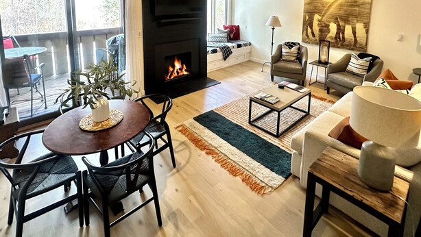 A modern living room with a fireplace, a dining area with a round table and chairs, and a seating area with a sofa and armchairs. - 2 Bed Remodeled Deluxe Mtn. Loft Minutes from Skiing JHMR (Wilson)