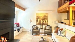 A modern living room with a fireplace, leather sofas, a coffee table, and a painting on the wall. - 2 Bed Remodeled Deluxe Mtn. Loft Minutes from Skiing JHMR (Wilson)