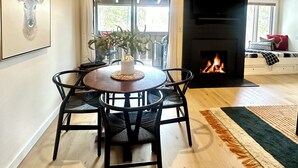 A dining area with a round table, chairs, a vase, and a fireplace. - 2 Bed Remodeled Deluxe Mtn. Loft Minutes from Skiing JHMR (Wilson)