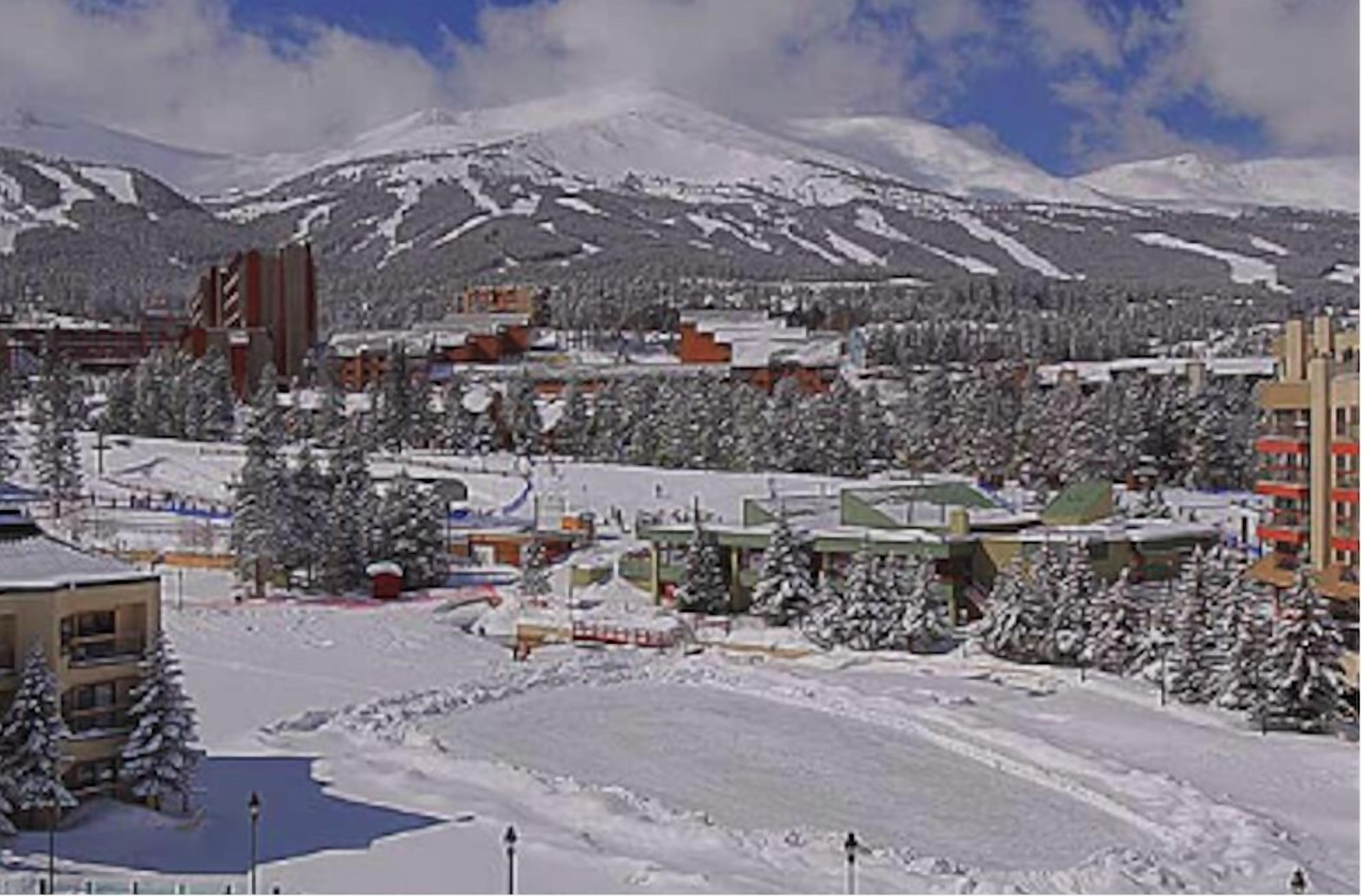 Un pueblo nevado con edificios y una montaña al fondo.