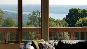 Une pièce dotée d’une grande fenêtre donnant sur un paysage magnifique, avec un lac et une forêt en toile de fond.