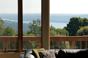A room with a large window overlooking a scenic view of a lake and forest.