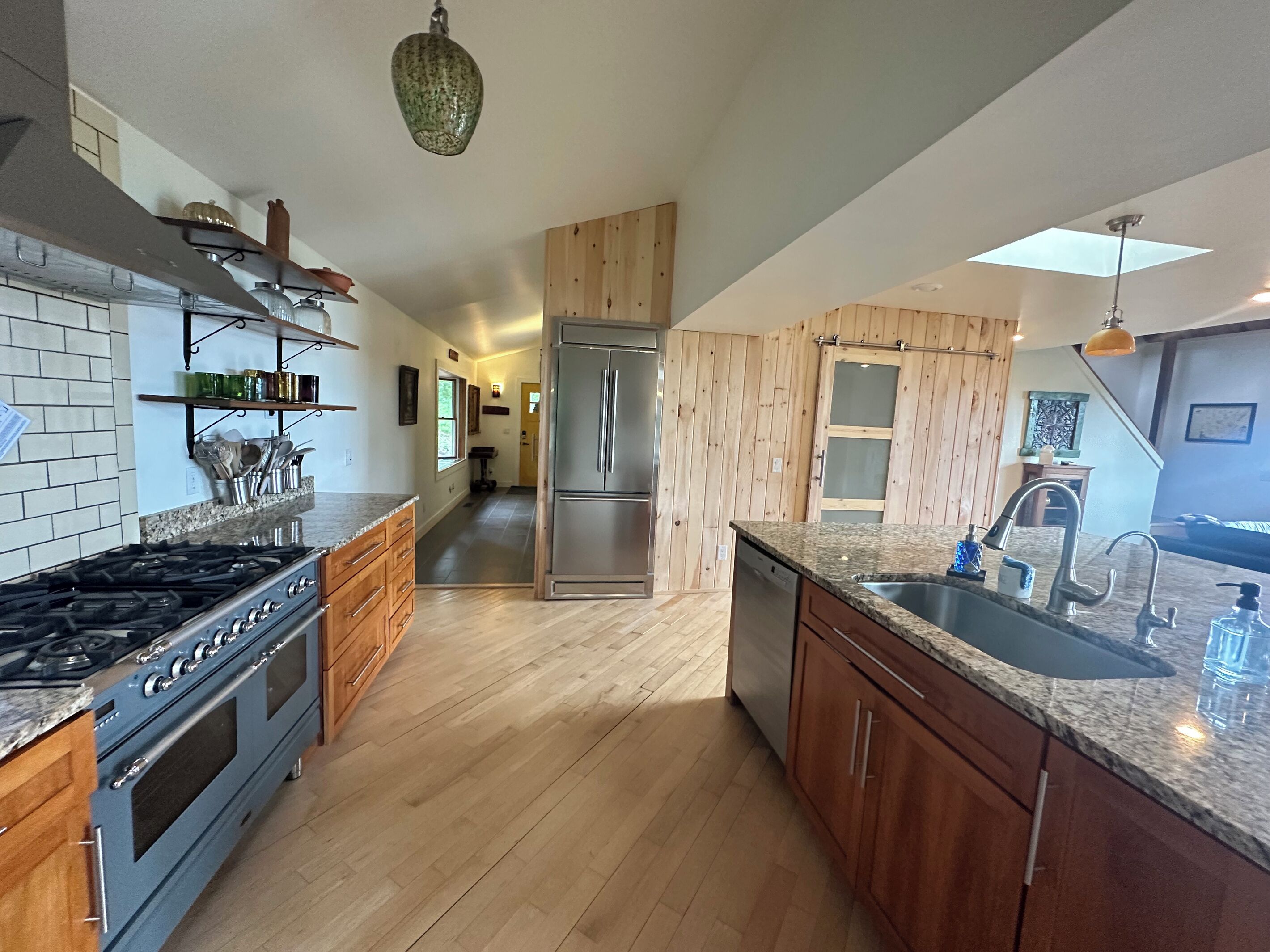 A spacious kitchen with wooden cabinets, a stainless steel refrigerator, and a granite countertop.