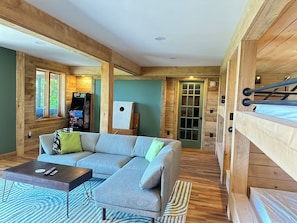 A cozy room with a sectional sofa, a coffee table, a gaming console, and a bunk bed.