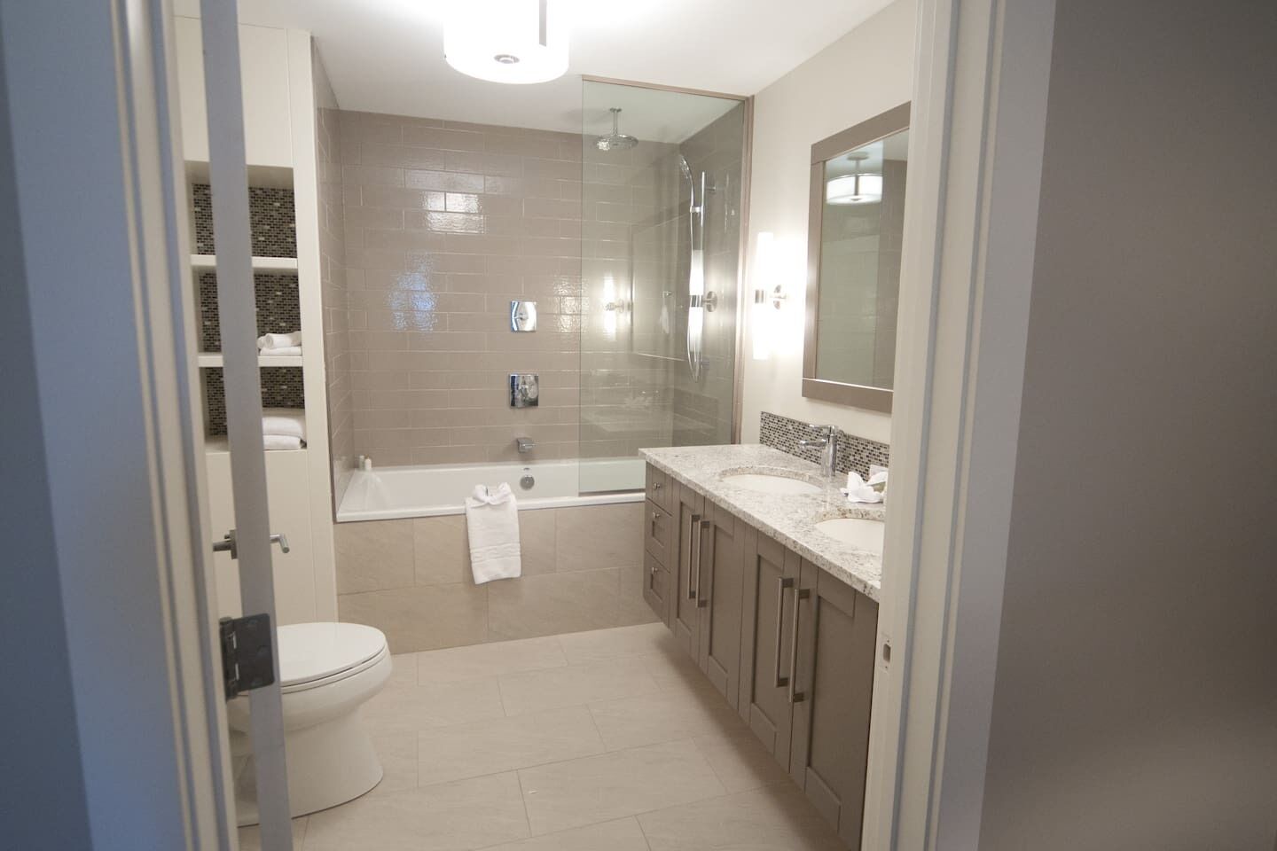 A modern bathroom with a glass-enclosed shower, a freestanding bathtub, and a vanity with a large mirror.