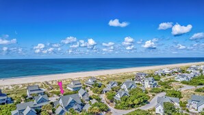 Uma área residencial costeira com casas, uma praia e céu limpo.