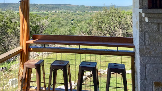 A balcony with a view of a green landscape and a stone wall. - Guadalupe River, Whitewater Amphitheater, New Braunfels, Canyon Lake, Gruene (New Braunfels)