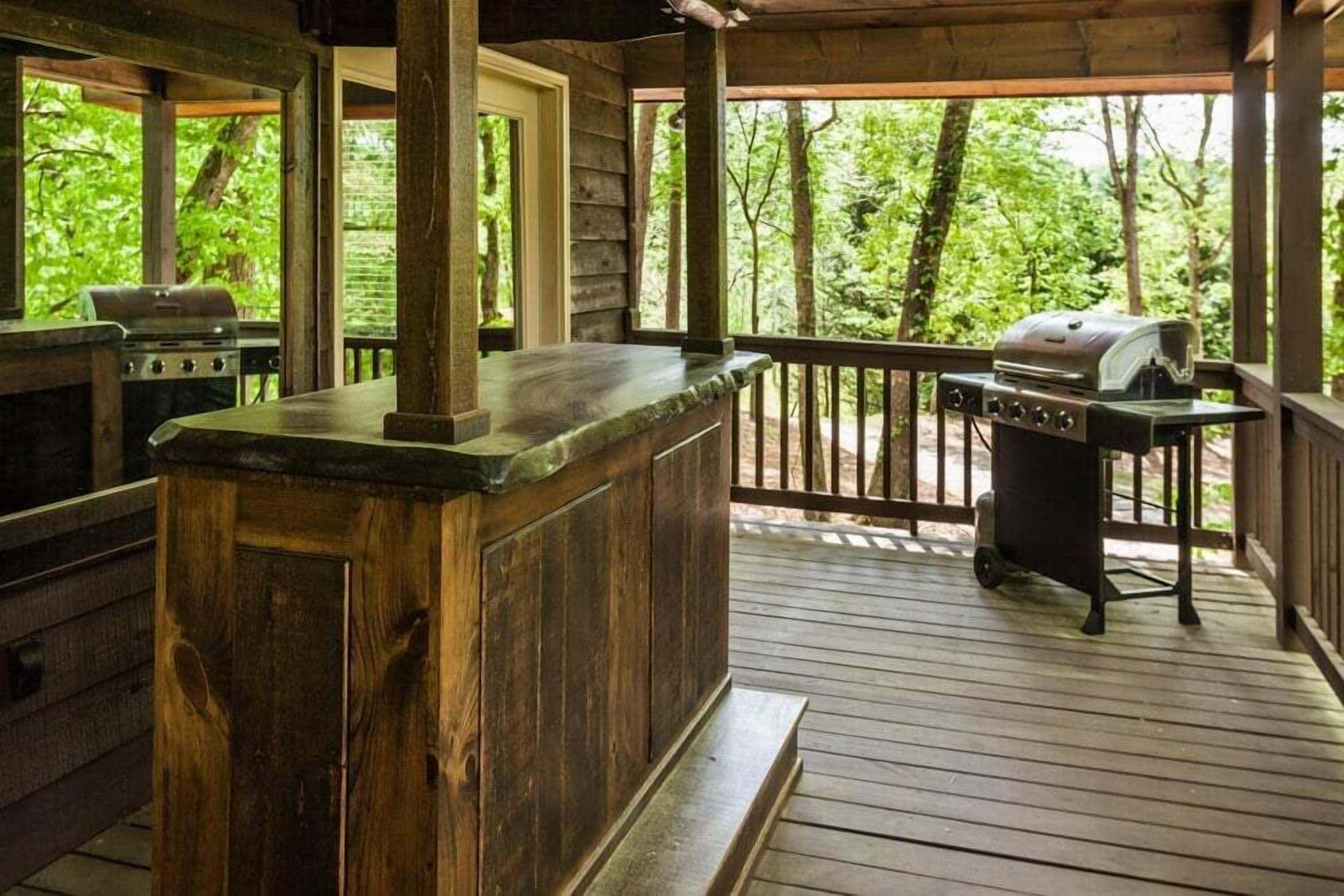 Un patio in legno con angolo bar, barbecue e vista sulla foresta.