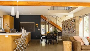 Una cocina moderna con barra, comedor y sala de estar, además de una escalera.