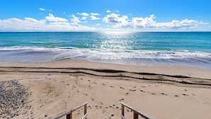 A beach with a wooden staircase leading down to the shore, sandy beach, and footprints in the sand. - OCEANFRONT CHIC LUXURY HOME (Capistrano Beach)
