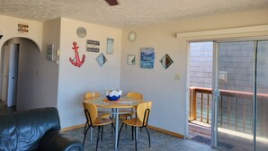 Un comedor con mesa y sillas, ventilador de techo y decoración mural.