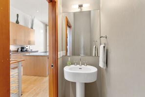 Ein modernes Badezimmer mit einem weißen Waschbecken, einem Spiegel und einem Handtuchhalter.