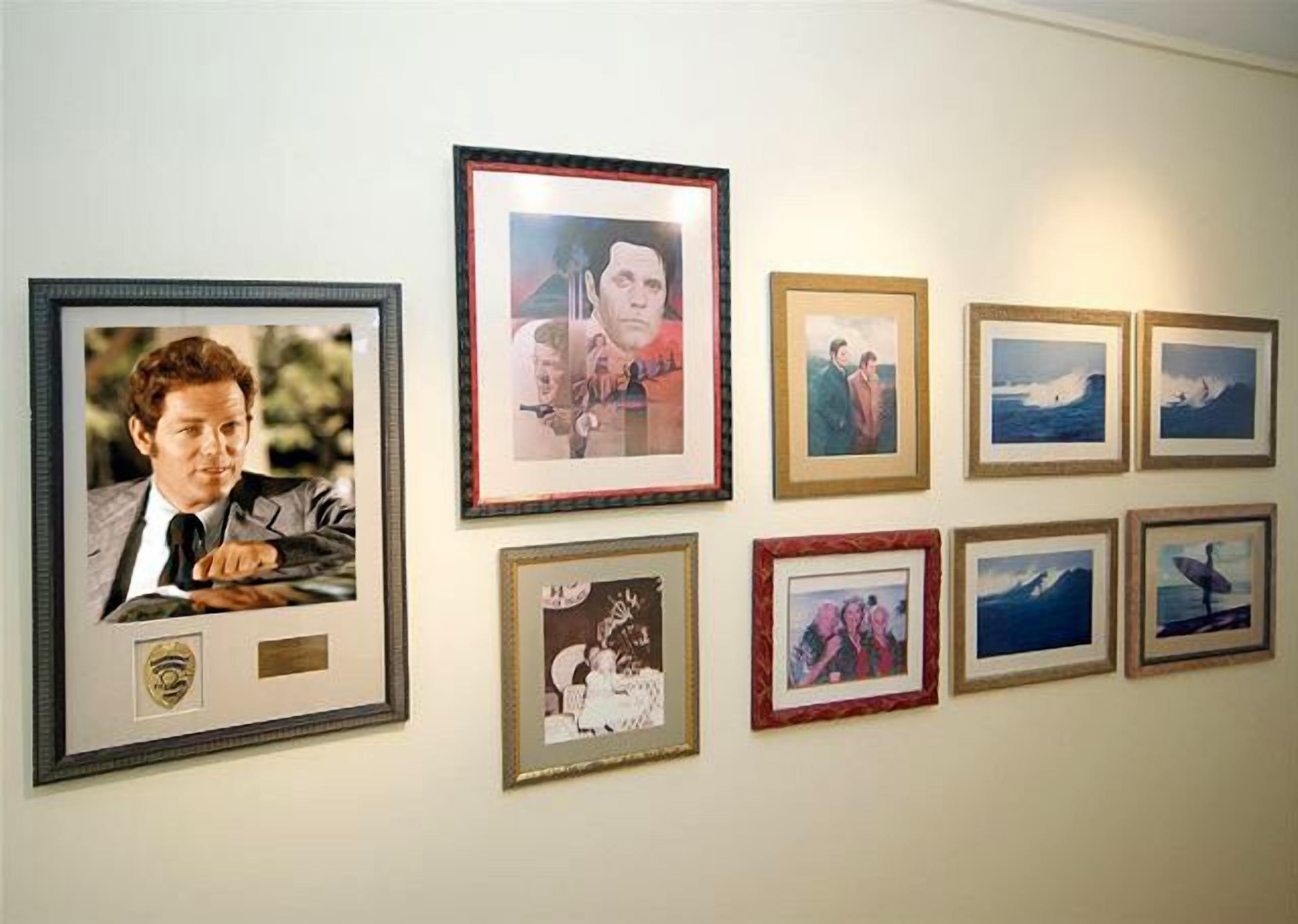 Un mur orné de divers tableaux encadrés, notamment des portraits et des paysages.