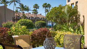 An outdoor patio with a table and chairs, surrounded by lush greenery and palm trees.