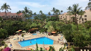 A resort with a swimming pool surrounded by palm trees and lounge chairs.