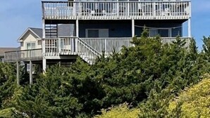 Un edifici de dues plantes amb un balcó al pis superior, envoltat de vegetació.