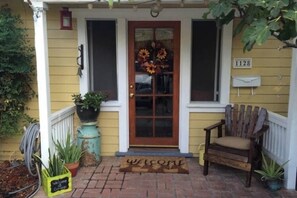 Welcome to a charming entrance, complete with a floral wreath and a cozy spot to sit and unwind.