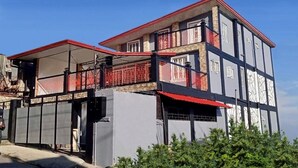 A multi-story building with a red roof and a balcony.