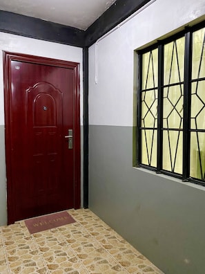 Stunning hallway with a patterned floor and a door on one side, and a window with a geometric design on the other.