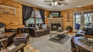 A cozy cabin interior with a fireplace, leather furniture, and a sign indicating establishment year. - Summers' Ridge by Mountain Oasis | Dog-Friendly Cabin in Coosawattee River Resort (Ellijay)
