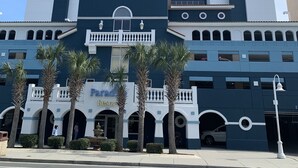 Un hotel de varios pisos con una torre central, un balcón y un letrero que dice "Paradise Resort".