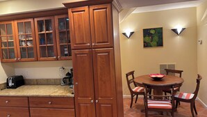 Una cocina con armarios de madera, encimera de granito y comedor con mesa y sillas.