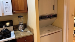 Una cocina compacta equipada con microondas, estufa, licuadora y un refrigerador pequeño.