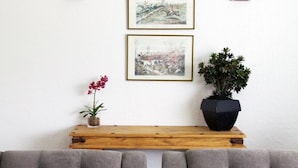 Una sala moderna con un sofá gris, una mesa de centro de madera y una planta en maceta.