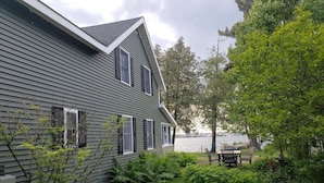 A house with a sloped roof and a garden with a pond and seating area. - Spacious Waterfront Home In Thousand Islands! (Ogdensburg)