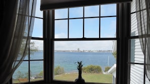 A window with a view of a body of water and a distant city skyline. - Spacious Waterfront Home In Thousand Islands! (Ogdensburg)