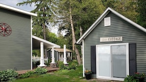A guest cottage with a covered porch, a sign reading "Guest Cottage," and a red compass decoration on the wall. - Spacious Waterfront Home In Thousand Islands! (Ogdensburg)