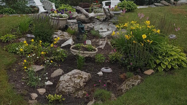 A garden with white Adirondack chairs, a stone pathway, and a view of a large body of water. - Spacious Waterfront Home In Thousand Islands! (Ogdensburg)