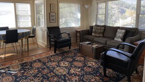 A living room with a wooden ceiling, large windows with blinds, a sofa with patterned cushions, a coffee table, and a patterned rug. - In the center of town with views of Longs Peak (Estes Park)