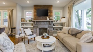 Una sala de estar con chimenea, un televisor montado encima y un sofá.