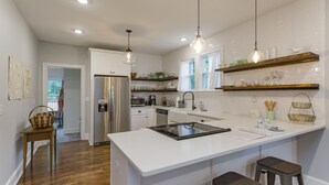 Una cocina moderna con armarios blancos, electrodomésticos de acero inoxidable y una isla central con taburetes.
