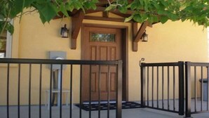 A building entrance with a wooden door, black metal gates, and a small outdoor seating area. - 1 BR guest house overlooking a beautiful vineyard  (oliver)