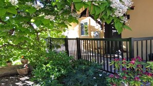 A garden with a black metal fence, green foliage, and flowering plants. - 1 BR guest house overlooking a beautiful vineyard  (oliver)