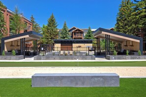 Un bâtiment moderne doté d’un espace extérieur aménagé avec une zone de repos couverte, d’une piscine et d’une pelouse bien entretenue.