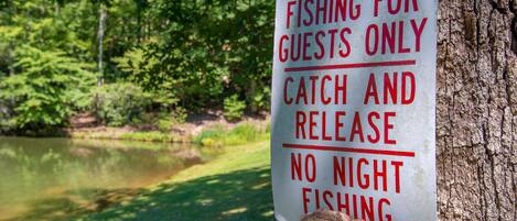 A sign on a tree stating "FISHING FOR GUESTS ONLY, CATCH AND RELEASE, NO NIGHT FISHING".