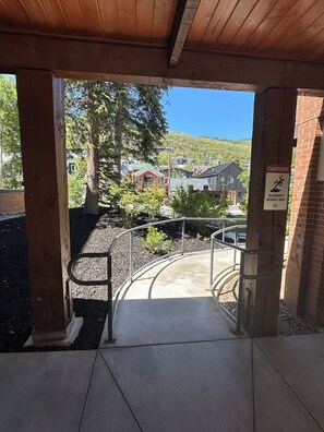 A covered outdoor area with a metal railing, a caution sign, and a view of houses and trees.