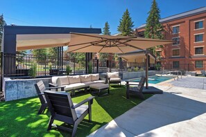 An outdoor patio with a pool, seating area, and a covered section.